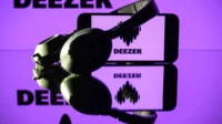 This photograph taken on January 13, 2025 in Toulouse shows headphones beside a smartphone and a computer screen displaying the logo of the French music streaming platform Deezer.
