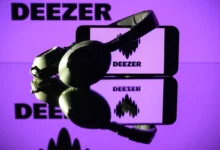 This photograph taken on January 13, 2025 in Toulouse shows headphones beside a smartphone and a computer screen displaying the logo of the French music streaming platform Deezer.