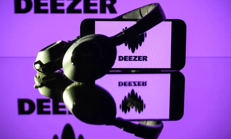 This photograph taken on January 13, 2025 in Toulouse shows headphones beside a smartphone and a computer screen displaying the logo of the French music streaming platform Deezer.